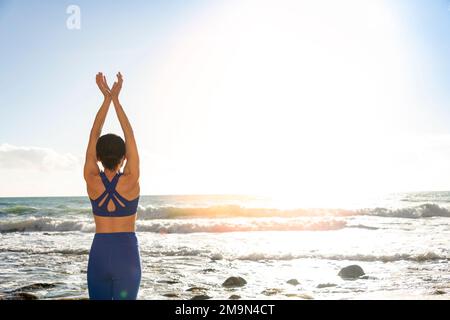 Weibliche Schwimmerin steht am Strand und macht Dehnübungen Stockfoto