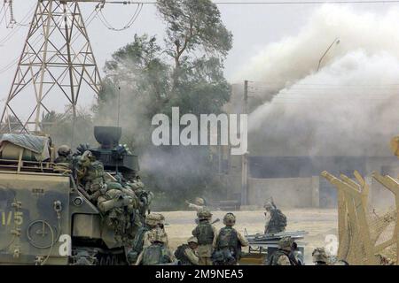 Mit Hilfe ihres US Marine Corps (USMC) Assault Amphibian Vehicle, Personal (AAVP7A1), USMC Truppe von Charlie Company, 1. Bataillon, 5. Marines, 1. Marine Division aus Camp Pendleton, Kalifornien, zerstören eine feindliche Scharfschützenposition in einem Gebäude, um die Freiheit der Operation IRAQI zu unterstützen. Operation/Serie: IRAKISCHE FREIHEITSBASIS: Bagdad Land: Irak (IRQ) Stockfoto