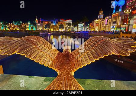 DUBAI, Vereinigte Arabische Emirate - 6. MÄRZ 2020: Die Skulptur des Goldenen Adlers vor den hell erleuchteten Pavillons des Global Village Dubai, am 6. März in Dubai Stockfoto