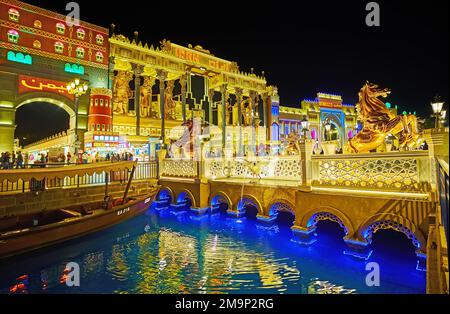 DUBAI, Vereinigte Arabische Emirate - 6. MÄRZ 2020: Prunkvolle Food Bridge mit goldenen Statuen der Pferdeaufzucht gegen Pavillons des Global Village Dubai, am 6. März in Dubai Stockfoto