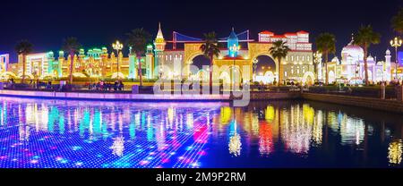 DUBAI, Vereinigte Arabische Emirate - 6. MÄRZ 2020: Panorama mit beleuchteten Pavillons verschiedener Länder und LED-Unterwasserschirm im Teich des Global Village Dubai, auf der M Stockfoto