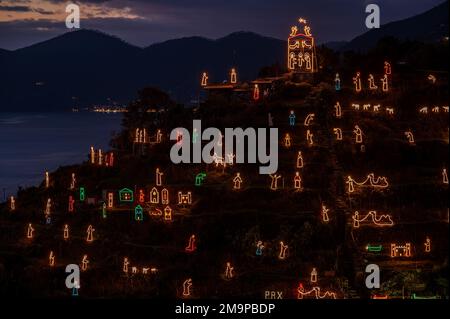 Beleuchtete Geburtsszene auf einem Hügel über dem Dorf Manarola in Cinque Terre in der Dämmerung Stockfoto