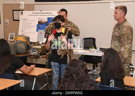 Sgt. 1. Class Drew Oliver (rechts) und Staff Sgt. Ahmed Elinbabi aus den USA Die Airborne Test Force von Army Yuma Proving Ground (YPG) unterstützt einen Freiwilligen, der am 20. Mai einen Fallschirm ausprobiert, bei einem Karrieretag, der von der Somerton Middle School in Somerton, Arizona, veranstaltet wird. Die beiden Soldaten und vier zivile Ingenieure sprachen mit sechs verschiedenen Klassenzimmern voller Studenten über die wichtige Mission von YPG, bei der praktisch alle Ausrüstungsgegenstände getestet wurden, die ein Soldat wahrscheinlich schießen, fahren oder tragen wird. Stockfoto