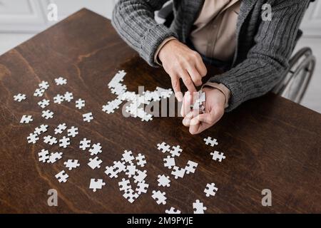 Partielle Ansicht eines behinderten Mannes mit parkinson-Krankheit halte Elemente des Puzzles in zitternden Händen, Stock Image Stockfoto