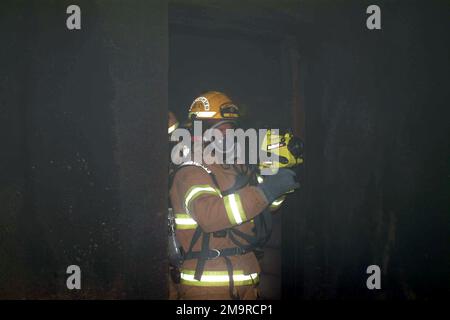 Kenny Padgett, ein Feuerwehrmann bei der Structural Fire Division (SFD) der Marine Corps Air Station Beaufort (MCAS) in Beaufort, South Carolina (SC), betritt während einer Übung ein rauchgefülltes Gebäude, um Feuerwehrleute mit einem neuen Gerät namens Wärmebildkamera vertraut zu machen. Die Wärmebildkamera erkennt Wärme ähnlich wie eine Infrarotkamera. So können Feuerwehrleute sowohl Feuer, das in den Wänden verborgen sein könnte, als auch Opfer, die sie sonst nicht finden könnten, lokalisieren. Basis: MCAS, Beaufort Bundesstaat: South Carolina (SC) Land: Vereinigte Staaten von Amerika (USA) Stockfoto