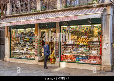 Eine Frau schaut sich Osterbonbons an, im Fenster eines Süßwarenladens in einer Fußgängerzone von Venedig, Italien. Stockfoto