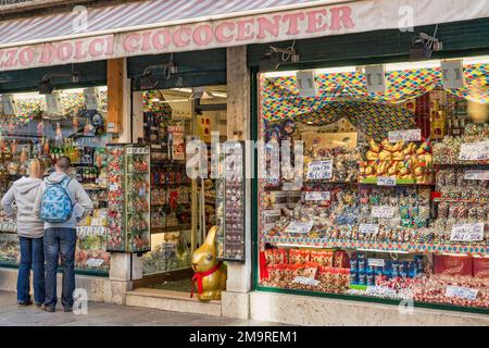 Ein Paar sieht sich Osterbonbons im Fenster eines Süßwarenladens in einer Fußgängerzone von Venedig, Italien, an. Stockfoto