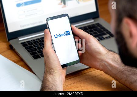 LinkedIn-App auf dem Smartphone-Bildschirm. Mann mit einem Telefon mit einer professionellen und geschäftsorientierten Social-Network-Service-Anwendung. Stockfoto