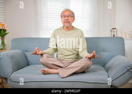 Ein alter asiatischer Mann übt Yoga und Meditation in Lotusposition und mit geschlossenen Augen Stockfoto