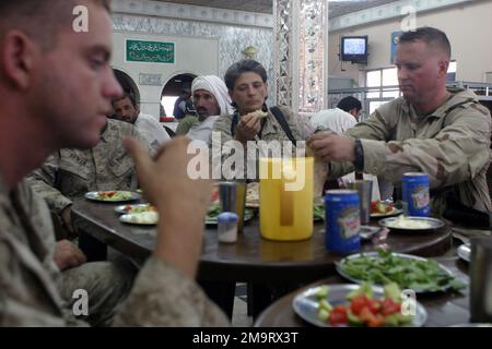 US Marine Corps Reserve (USMCR) Marines essen während der Operation IRAQI FREEDOM in einem lokalen irakischen Restaurant in der Nähe von Suwayrah, Irak, zu Mittag. Von links nach rechts abgebildet sind: Lance Corporal (LCPL) Ivey, Surveillance and Target Acquisition Platoon, 3. Bataillon, 23. Marineregiment (3/23); GUNNERY Sergeant (GYSGT) Heidi Schuerger, SENIOR Non-commissioned Officer (SNCO), 4. Civil Affairs Group (CAG); UND MASTER Charge (MSGT) im Visual Combat-Offizier (CVMORIC), James MARRCORORIC (CVMORIC). Subjekt Operation/Serie: IRAKISCHE FREIHEITSBASIS: Als Suwayrah Count Stockfoto