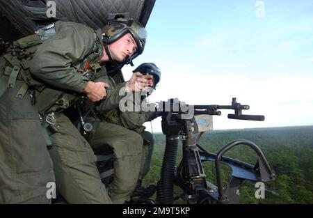 US Marine Corps (USMC) Lance Corporal (LCPL) Jason Kingsland, vom Marine Helicopter Light Attack Squadron 773 (HMLA-773) an Bord eines UH-1N Iroquois Twin Huey Helikopters zielt mit einer an der Tür montierten M-60 7,62mm Maschinenpistole, während Sergeant Brian 'Soup' Cambell links Ruft Anweisungen während einer Live-Feuertraining-Mission über dem Luftwaffenstützpunkt Eglin (AFB), Florida. Basis: Luftwaffenstützpunkt Eglin Bundesstaat Florida (FL) Land: Vereinigte Staaten von Amerika (USA) Stockfoto