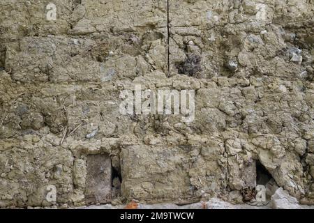 Alte, bei Renovierungsarbeiten freigelegte, klumpige Hauswand aus Ton Stockfoto