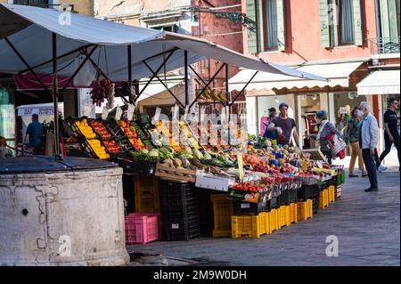 Ein Anbieter von Outdoor-Produkten, der eine Handvoll Chiles hält, spricht mit einem Kunden im historisch jüdischen Teil von Venedig. Stockfoto