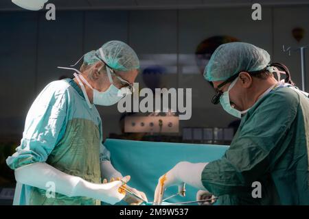 Chirurgie am offenen Herzen Arzt führt Operation am offenen Herzen durch. Ärzte in grünen Uniformen sind im Operationssaal Stockfoto
