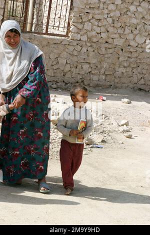 040326-M-5150A-033. [Complete] Scene Caption: Eine örtliche Irakerin (Cener) hält die Hand eines ihrer Kinder (links), während ihr kleiner Sohn (rechts) neben ihr geht und ein Flugblatt hält, das ihm vom US Marine Corps (USMC) Marines, Headquarters and Service Company (H&S Co), 2. Bataillon (BN), 7. Marine Regiment gegeben wurde (2./7. MÄRZ), 1. Marine Division (MARDIV) und US Army (USA) Soldaten, Psychological Operations (PSYOPS), dem MARDIV VON 1. angehängt, warnen alle irakischen Kinder, keine Waffen auf einen US- oder Koalitionssoldaten zu richten. Dieser Prospektvertrieb wurde während eines USMC durchgeführt Stockfoto