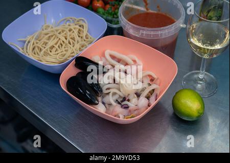Rohe Zutaten zum Kochen von Meeresfrüchte-Pasta - Spaghetti, Muscheln, Sauce, Limette, Tomaten und Weißwein Stockfoto