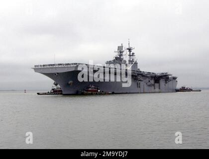 Eine Hafenbogenansicht der WASP-KLASSE der US Navy (USN): Amphibious Assault Ship, USS BATAAN (LHD 5), zeigt Matrosen, die die Schienen besetzen, während das Schiff von kommerziellen Schleppbooten unterstützt wird, nachdem es nach einer 72-tägigen Entsendung zur Unterstützung der Freiheit der Operation IRAQI zu seinem Homeport in Naval Base Norfolk, Virginia (VA) zurückgekehrt ist. Basis: Marinestützpunkt, Norfolk Bundesstaat: Virginia (VA) Land: Vereinigte Staaten von Amerika (USA) Stockfoto