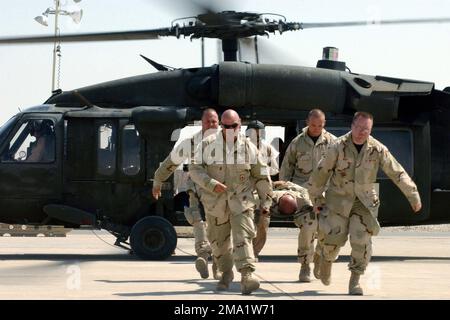 040626-F-3715H-023. [Complete] Szene Caption: US Air Force (USAF) Captain (CPT) Kevin West, 407. Expeditionary Medical Group (EMDG), USAF Technical Sergeant (TSGT) Jerame Bullard, 407. Expeditionary Civil Engineering Squadron (ECES), Und USAF STAFF Sergeant (SSGT) Daniel Morris, 407. ECES, üben, einen Patienten auf einem Wurf eines MH-60 Blackhawk (Black Hawk) Hubschraubers der US Army (USA) zu transportieren. Die Schulung, durchgeführt von der USA 43. Medical Company (Air Ambulance) (MED CO (AA)), wurde mit und ohne die Flügel des Helikopters durchgeführt. Die Luftwaffeneinheit der Armee leitet das Training für Stockfoto