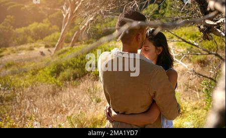 Natur, Liebe und ein Paar, das sich im Freien umarmt oder küsst, während es im Sommer einen intimen Moment miteinander verbringt. Feld, Landschaft und Küsschen mit einem Mann und Stockfoto