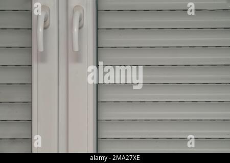 Fensterläden und Nahaufnahme, doppelflügeliges weißes Kunststofffenster, zwei Fenstergriffe Stockfoto