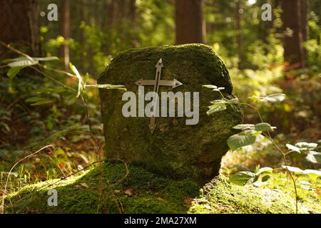 Das eiserne christliche Kreuz auf einem großen Stein im Wald Stockfoto