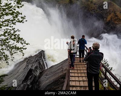 Man sieht, wie man Fotos vom beliebtesten Wasserfall Schwedens macht. Die skandinavischen Länder verfügen alle über einzigartige Landschaften, die nur dort zu finden sind. Daher ist es nicht überraschend, dass die skandinavischen Länder das ganze Jahr über unzählige Touristen empfangen. Schweden verfügt auch über mehr als tausend Meilen Küste. Jeder in Schweden kann die Wälder, die Berge, die Seen und das Meer genießen, dank des so genannten jedermanns Rechts. Weit oben im Norden sind die Sommer besonders besonders, da die Sonne ein paar Wochen lang gar nicht untergeht, immer noch um Mitternacht scheint und die umliegenden Landschaften in sich aufnimmt Stockfoto