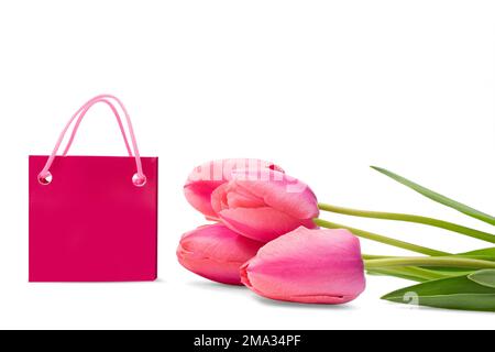 Pinkfarbene Tulpen mit grünen Blättern und Einkaufstasche liegen auf einem weißen, isolierten Hintergrund. Feiertage, Internationale Frauen, Muttertag, Geburtstag, 8. März, sal Stockfoto