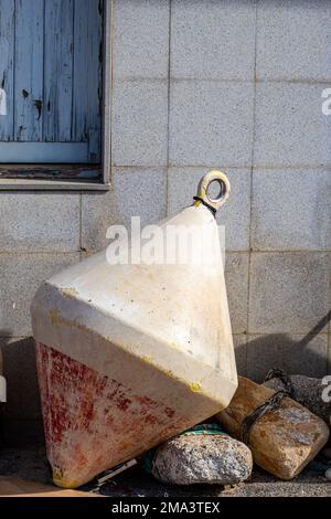 Große weiße und rote Meeresboje über dem Boden im Fischereihafen des Dorfes Blanes in Katalonien. Stockfoto