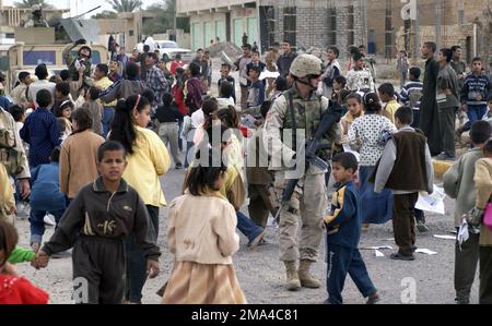 041116-F-2034C-041. [Complete] Filmtitel: US Army (USA) Specialists (SPC) William Randall zugewiesen zu Charlie Truppe, 1-4. Kavallerie, 1. Infanteriedivision, Er trägt sein 5,56mm-mm-M16A2-Gewehr in Bereitschaft, während er sein Team und die irakische Nationalgarde (ING) während der Operation IRAQI FREEDOM Flyer und Süßigkeiten für Operation Paper Cut in Ad DWR, Irak, verteilt. Paper Cut ist eine Informationsaktion, die von Charlie Truppe und der irakischen Nationalgarde durchgeführt wird, um den Einfluss des Antiirakers in der Gegend zu verhindern, indem Flyer verteilt werden, die die lokalen Iraker wissen lassen, dass sie hier sind, um eine zu bauen Stockfoto