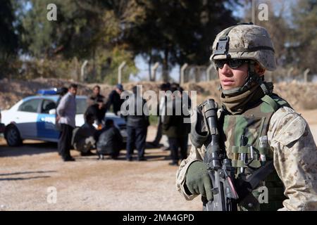 Bewaffnet mit einem Colt 5,56mm M16A2 Angriffsgewehr, US Marine Corps (USMC) Lance Corporal (LCPL) Caleb Macheski mit der Military Police (MP) Bravo Company, 1. Bataillon, 7. Marines sorgen für Sicherheit, während die irakische Polizei während der Operation IRAQI FREEDOM zur Arbeit an der Polizeiakademie in Al Qaim, Irak (IRQ) erscheint. Operation/Serie: IRAKISCHE FREIHEITSBASIS: Al Qaim Staat: Al Anbar Land: Irak (IRQ) Stockfoto