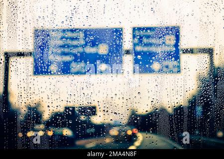 Fallenlassen auf einer regendurchfluteten Windschutzscheibe auf der Autobahn. Stockfoto