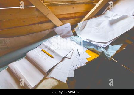 Masons Schreibtisch in einer Holzkabine mit einem Stapel architektonischer Zeichnungen, Papierlayouts und Plänen. Stockfoto