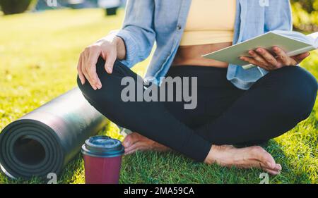 Nahaufnahme der Beine einer Frau, die im Frühling im Park Buch liest. Porträt des Lebensstils der Menschen. Stockfoto