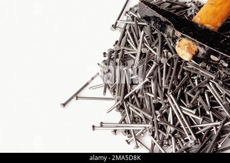 Eine Gruppe von Schreiner-Nägeln, die mit einem alten Holzhammer auf einem weißen Arbeitstisch gestapelt wurden. Stockfoto
