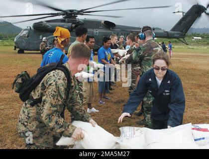 050124-N-0168J-001. [Complete] Szene Caption: US Marine Corps (USMC) Corporal (CPL) Tyler Samms (links) und US Navy (USN) Fire Controlman Third Class (FC3) Bethany A. Tote überreichen Reistüten an Matrosen und Marines während einer gemeinsamen Arbeitsgruppe mit ausländischen Streitkräften, um den USN MH-53E Sea Dragon Helikopter zu beladen, Helicopter Mine Gegenmaßnahmen Squadron 15 (HM-15), Blackhawks, Naval Station (NS) Norfolk, Virginia (VA). Das Wasp Class Amphibious Assault Ship USS ESSEX (LHD 2) [nicht abgebildet], Besatzungsmitglieder wurden zu einem Flugplatz in Sabang, Indonesien, geflogen, um Hubschrauber mit Süßwasser, Nahrung, CL Stockfoto