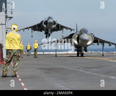 Ein US Marine Corps (USMC) AV-8B Harrier II, Marine Attack Squadron 513 (VMA-513) bereitet sich auf die Landung an Bord des Flugdecks der US Navy (USN) Tarawa Class Amphibious Assault Ship USS PELELIU (LHA 5) vor, während ein zweiter Harrier auf das Startsignal wartet. VMA-513 ist an Bord der USS PELELIU und führt Flugoperationen im Pazifik vor der südkalifornischen Küste durch. Basis: USS Peleliu (LHA 5) Land: Pazifik (POC) Stockfoto