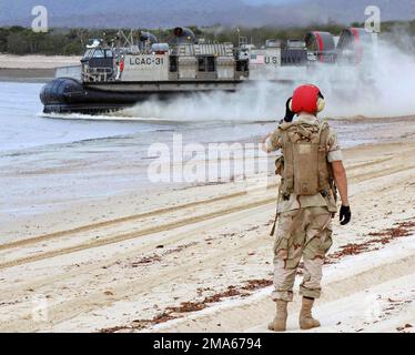050619-N-3455P-002. [Complete] Szene Caption: Ein US Navy (USN) Beachmaster, Assault Craft Unit 5 (ACU-5), Marine Corps Base (MCB) Camp Pendleton, Kalifornien (CA), an Bord des USN Wasp Class Amphibious Assault Ship USS BOXERS (LHD 4), sieht ein USN Landing Craft, Air Cushion (LCAC) Fahrzeug fährt nach der Absetzung von Soldaten der australischen Armee am Sabina Point während der Übung TALISMAN Sabre 2005 ab. TALISMAN Sabre ist eine Übung, die gemeinsam vom US Pacific Command (USPACOM) und dem Joint Operations Command der Australian Defense Force gesponsert wird und zur Ausbildung des Personals des US-Befehlshabers der 7.-Flotte und dient Stockfoto