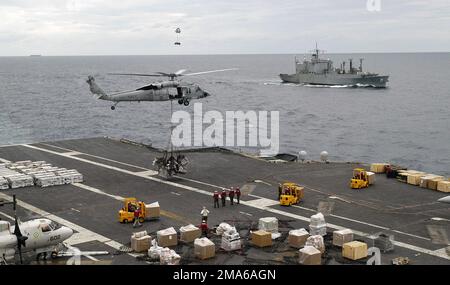 050627-N-0167B-021. [Complete] Scene Caption: A U.S. Navy MH-60s Seahawk Helicopter, Helicopter Sea Combat Squadron 25, transportiert im Hintergrund Fracht an Bord des Flugzeugs Carrier USS KITTY HAWK (CV 63) des militärischen Sealift Command Kilauea Class Munitionsschiffs USNS FLINT (T-AE 32), Während einer vertikalen Wiederauffüllung zwischen den beiden Schiffen während der Übung Talisman Sabre 2005 vor der Küste der australischen Region Queensland am 27. Juni 2005. Talisman Sabre ist ein US-amerikanischer Pacific Command-Übung zur Ausbildung der USA Siebter Flottenkommandant und australische gemeinsame oper Stockfoto