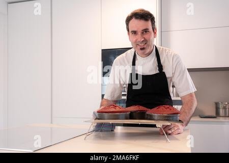 Ein Bäcker backt zu Hause einen roten Samtkuchen, der in den Ofenformen gebacken wird Stockfoto