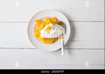Teller mit gehackten Orangen und griechischem Joghurt isoliert auf weißem Hintergrund. Natürlicher Snack für Fitness, Training, gesunde Ernährung und Ernährung. Flach verlegt Stockfoto