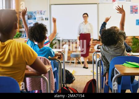 Ich liebe es, einen verlobten Kurs zu sehen. Eine nicht wiedererkennbare Gruppe von Kindern, die im Klassenzimmer sitzen und die Hand heben, um eine Frage zu beantworten. Stockfoto