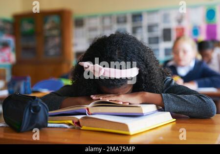 Ich will nur nach Geh nach Hause. Ein nicht wiedererkennbares Mädchen, das tagsüber in ihren Büchern in ihrem Klassenzimmer schläft. Stockfoto