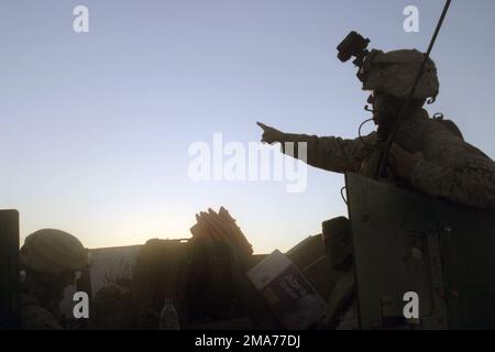 CAPTAIN (CPT) DES US Marine Corps (USMC) Corry Murphy, Forward Air Controller (FAC), 4. Platoon (PLT), Golf Company (G CO), 2. Bataillon (BN), 2. Marines (2/2), zeigt auf den nächsten Ort während der systematischen Absperrung und durchsucht die Stadt Albu Awda. Die Marines suchen bei Aufstandsbekämpfungsoperationen mit irakischen Sicherheitskräften (ISF) nach hochwertigen Zielen für Aufständische sowie nach illegalen Waffen und Munition, um während der Operation HEIMLICH im Rahmen der IRAKISCHEN FREIHEIT die antiirakischen Kräfte zu isolieren und zu neutralisieren. Basis: Albu Awda Staat: Al Anbar Land: Irak (IRQ) Stockfoto