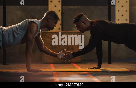 Intensives Workout. Zwei junge Männer, die zusammen Liegestütze machen. Stockfoto