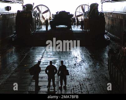 US Marine Corps (USMC) Marines, 22. Marine Expeditionary Unit (MEU), Marine Service Support Group (MSSG), warten Sie auf dem Bohrlochdeck des US Navy (USN) Harpers Ferry Class Dock Landing Ship USS CARTER HALL (LSD 50), während ein Landefahrzeug Air Cushion (LCAC) Ausrüstung entlädt. Die CARTER HALL verließ kürzlich ihren Heimatort in der Naval Station (NS) Norfolk, Virginia (VA), für einen regelmäßigen Einsatz zur Unterstützung des Krieges gegen den Terror. Basis: Morehead City Bundesstaat: North Carolina (NC) Land: Vereinigte Staaten von Amerika (USA) Stockfoto