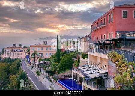 Taormina, Sizilien, Italien. Stadtbild der malerischen Stadt Taormina, Sizilien mit Vulkan Mt. Ätna im Hintergrund bei Sonnenuntergang. Stockfoto