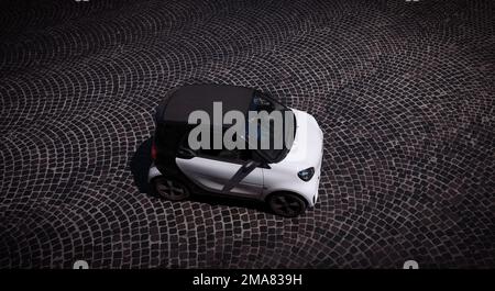 Ein weißes Smart-Auto, das von oben auf einer gepflasterten Straße in Rom fotografiert wurde, mit Kopierraum. Stockfoto