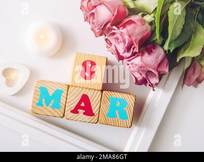 Hintergrund der Grußkarte zum internationalen Frauentag. Mit Holzherz, pastellfarbenen Blüten und Text 8. märz. Stockfoto