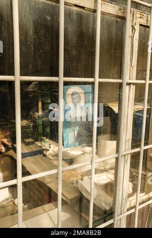 Alte Ladenfront in Belgrad, die verlassen oder stillgelegt aussieht, mit einem Porträt von Jesus im vorderen Fenster, das versperrt und mit Vorhängeschloss versehen ist. Stockfoto