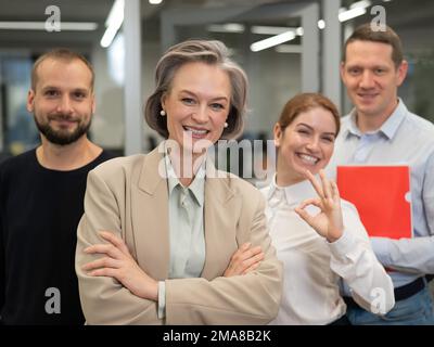 Porträt von vier Büroangestellten. Eine grauhaarige, reife Frau, ein weißer Mann, ein bärtiger Mann und eine rothaarige Frau. Stockfoto